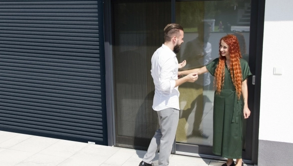 muž v košili a žena s plavými vlasy před domem