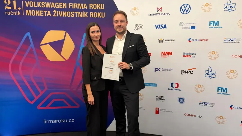 Dvojice s certifikátem LOMAX před soutěžní stěnou Firma roku 2026