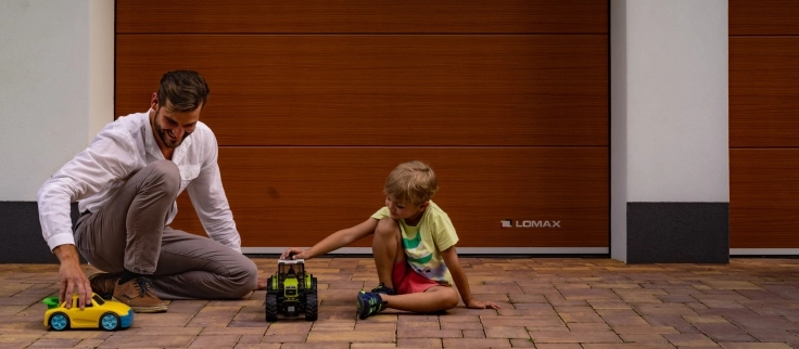 Otec a syn s hračkami před garážovými vraty LOMAX